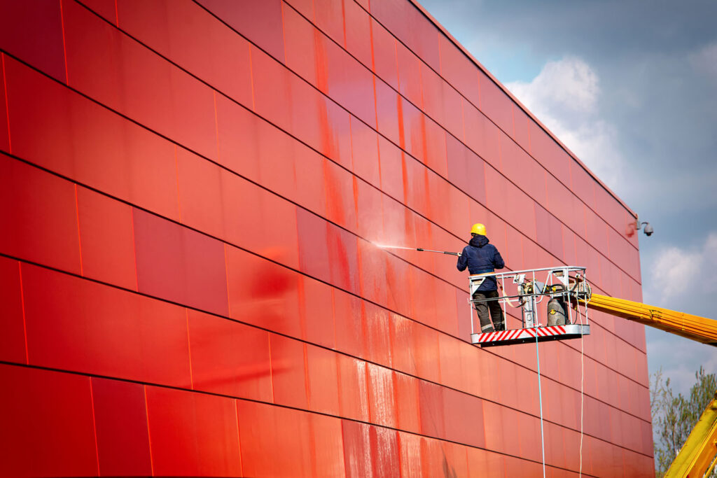 worker of Professional Facade Cleaning Services washing the red