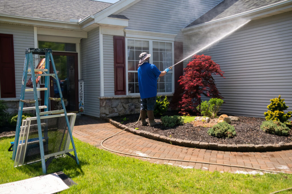 Man spraying a house with a pressure washer